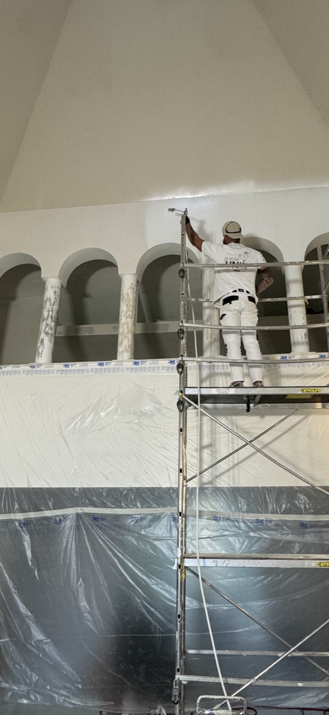 Peintre d'AIX PICCA sur échafaudage dans une pièce à arches en cours de rénovation