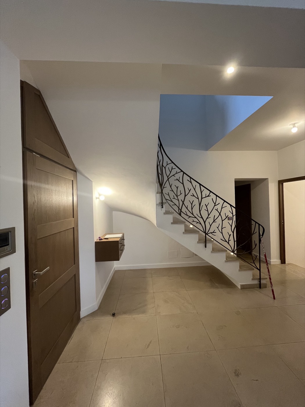 Cage d'escalier avec rampe en fer forgé motif branches et murs repeints