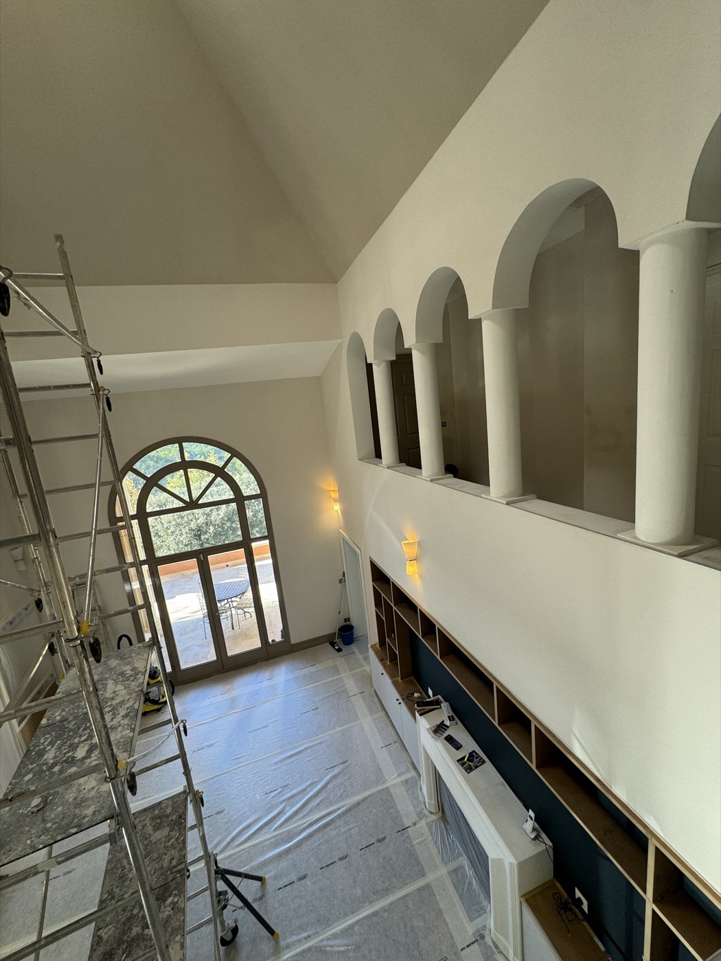 Galerie à arches et colonnes surplombant un séjour, murs repeints